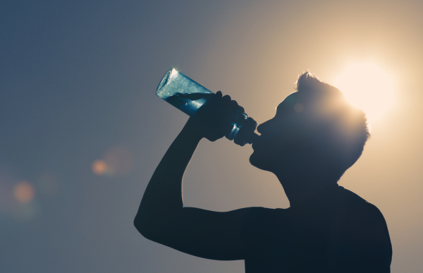 Drinking water from a reusable water bottle under the sun